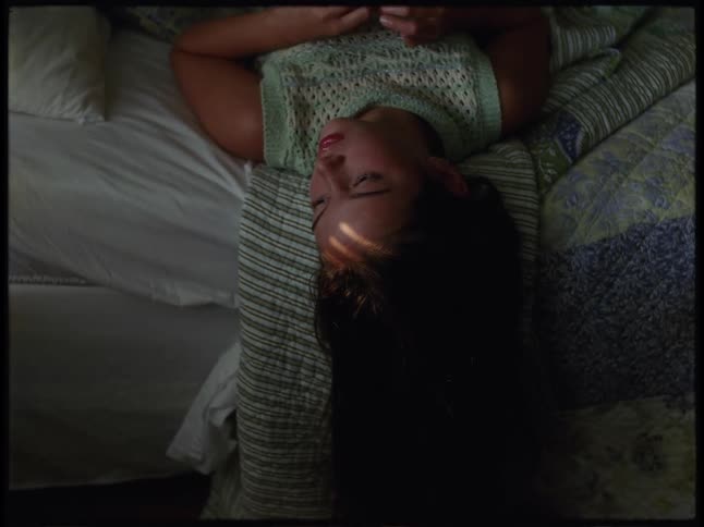 A woman contemplates as she looks from side to side while lying down