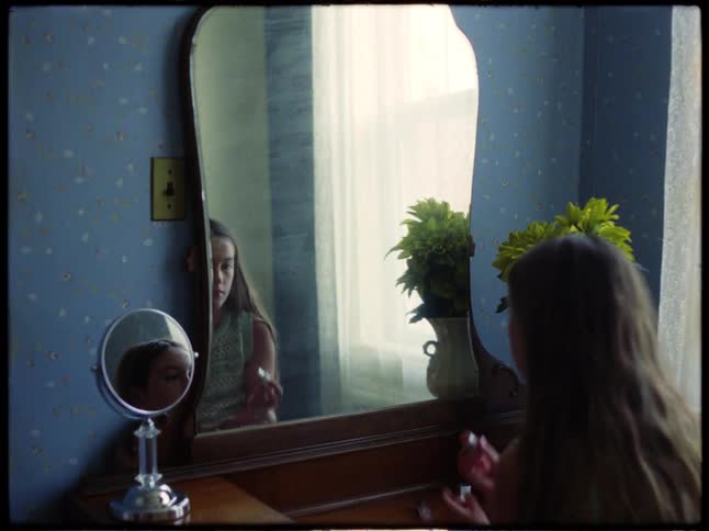 Girl applies makeup in front of a mirror