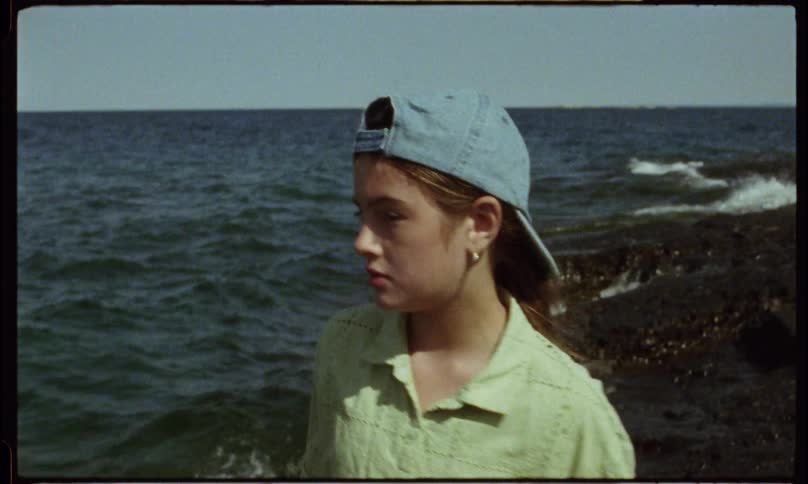 A female teenager and a child walk along the sea shore during the day