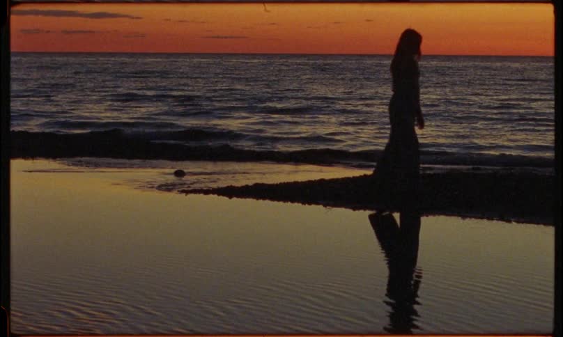 The silhouette of a person standing on the shore of the beach on a dark morning and then begins to walk