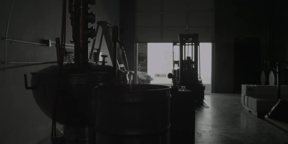 Water streams from a spigot into a barrel in a distillery or winery warehouse