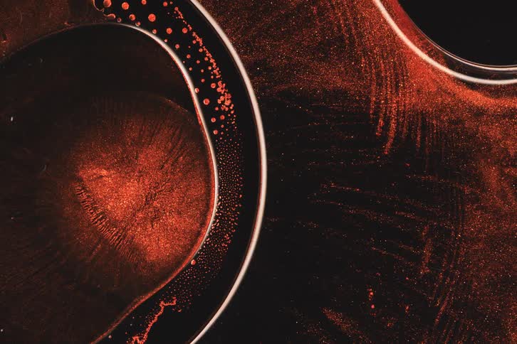 Extreme close up of a red liquid molecule moving against a black background