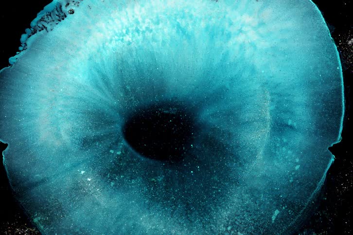 A bright blue liquid with several bright white dots that is moving
