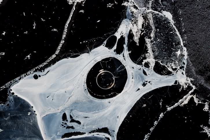 A black liquid with a white foam on the surface is on the floor