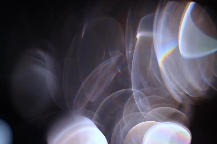 A highly abstract and blurry closeup of lens flares and soft light orbs creating a surreal and dreamy visual
