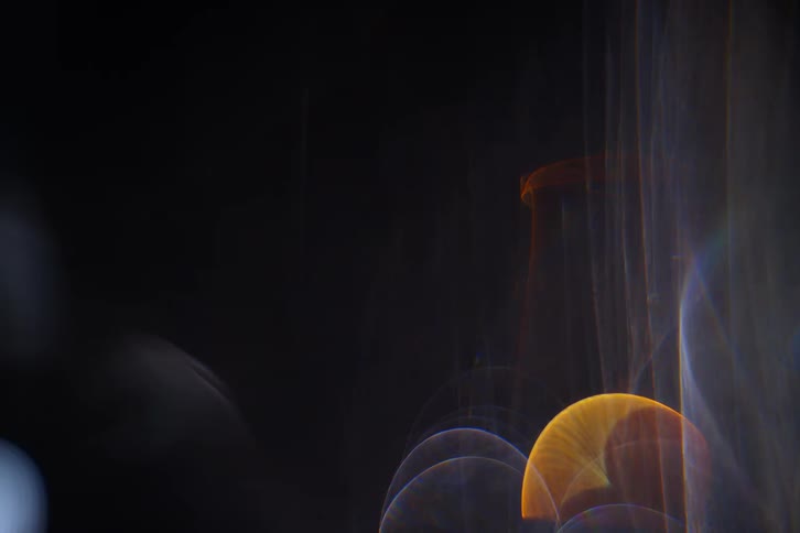 Light creates circular and cylindrical shapes on a dark background