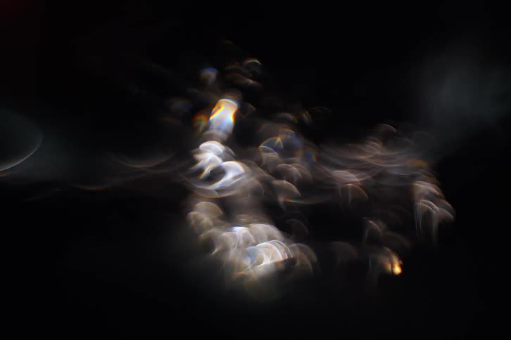 Abstract light patterns swirl and scatter across a dark background creating a dreamy outoffocus visual effect