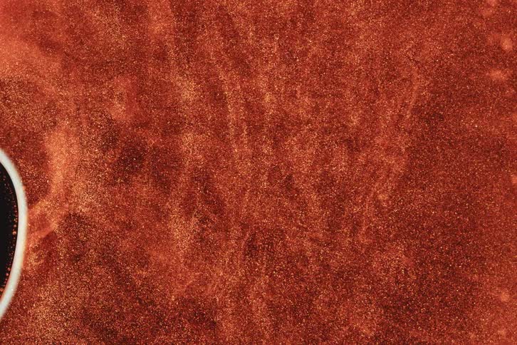 A rotating black center with a white aura causes orange particles to spread in a wave like pattern in a fluid
