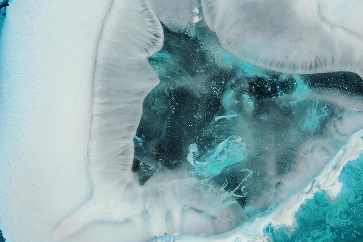 Surface of a mixture slowly freezes creating a layer of white over a mix of blues