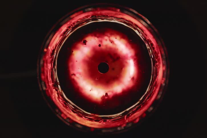 An abstract circular object of red color that is rotating on its own axis