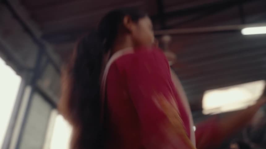 Women dance in saris inside a building