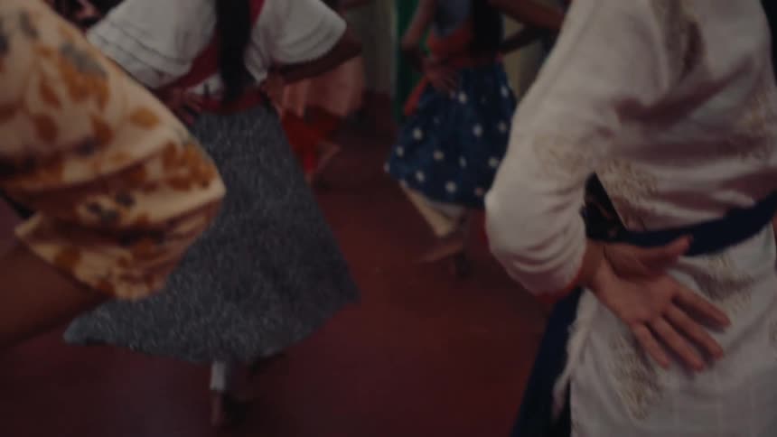 A group of children and children practice dance steps in a hall