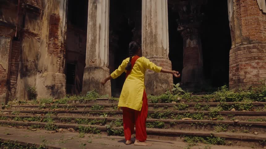 Three people dance on the steps of a decaying building contrasting movement with ancient ruins