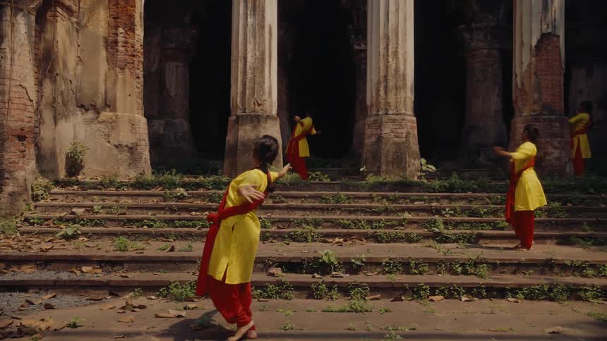 A few indian women dancing outside a burned out temple