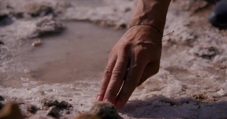 A man touches the frost on the ground