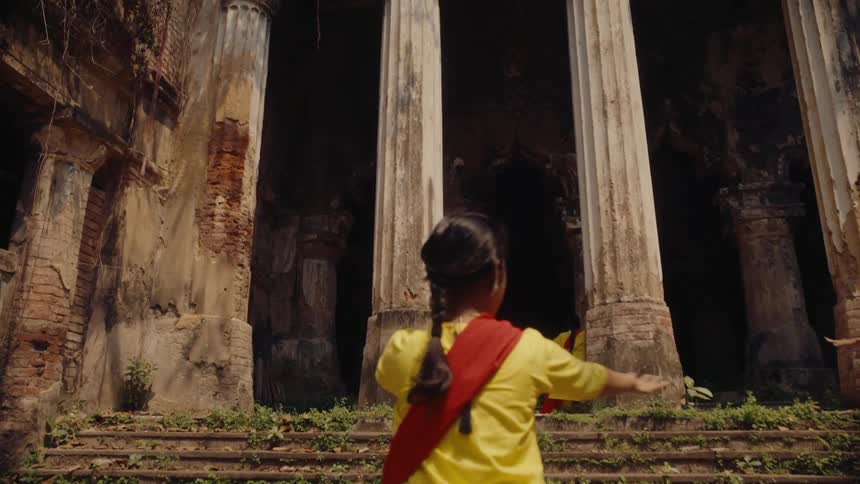 Four indian women performing an odissi dance near a temple
