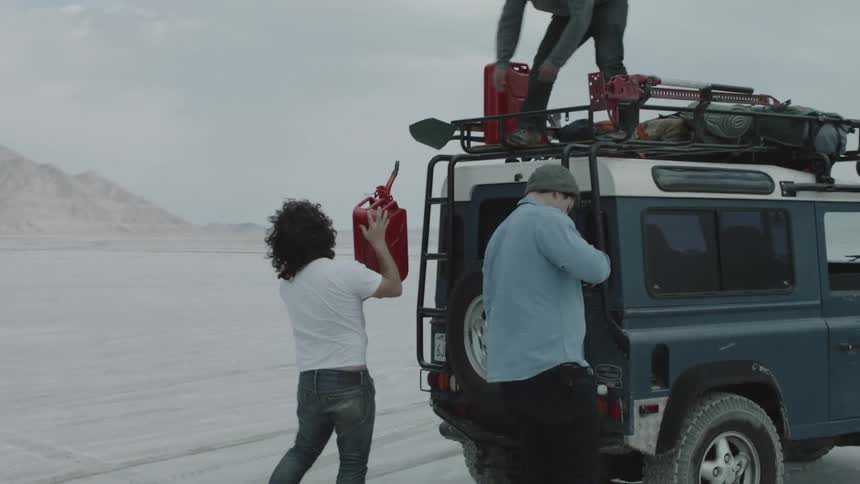 Men refueling a vehicle in the desert