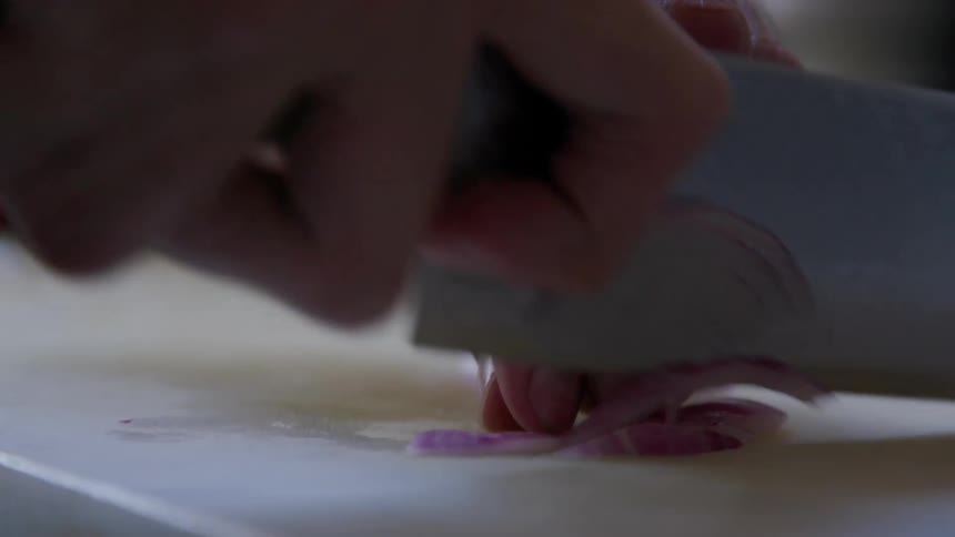 Close up of a person cutting onions on a board