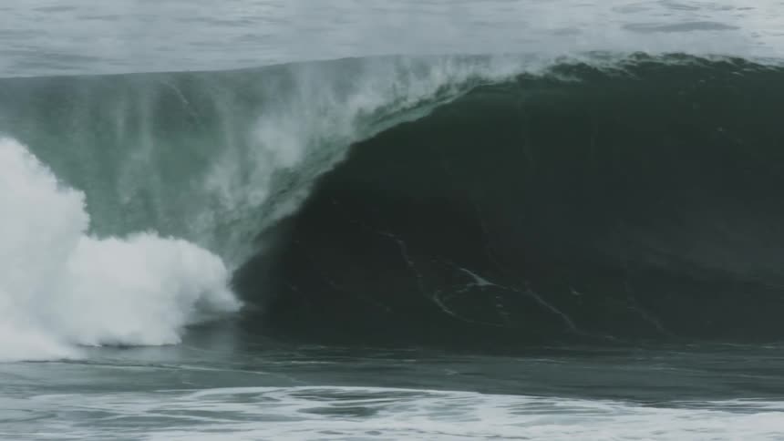 Huge wave splashes and curls as it rolls in to shore