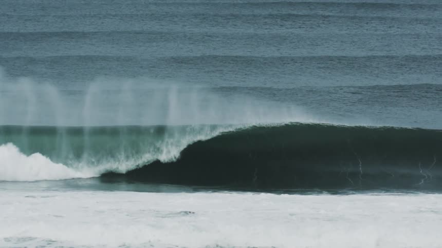 Aerial of large wave forming and crashing in the ocean