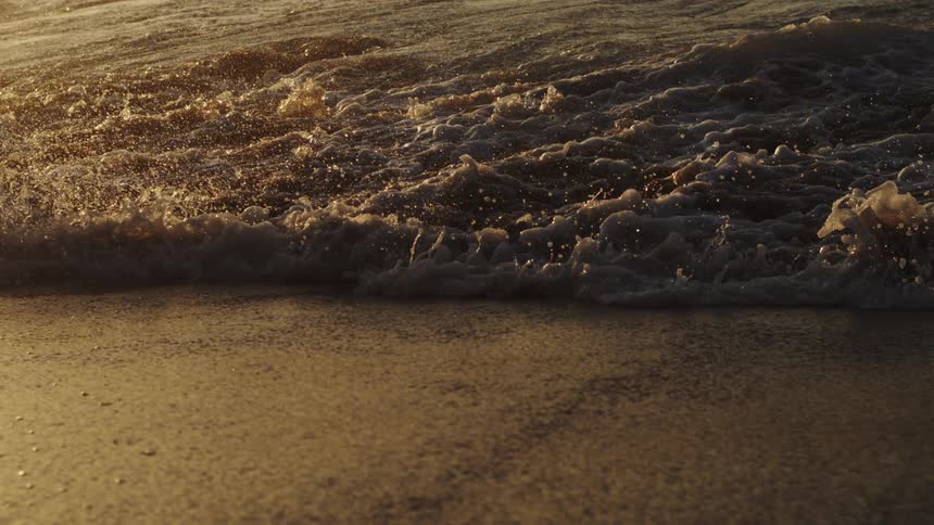 Waves splash and water droplets sparkle as they roll in to shore