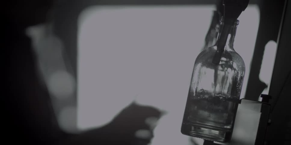 A tap pours a clear fluid into a glass bottle