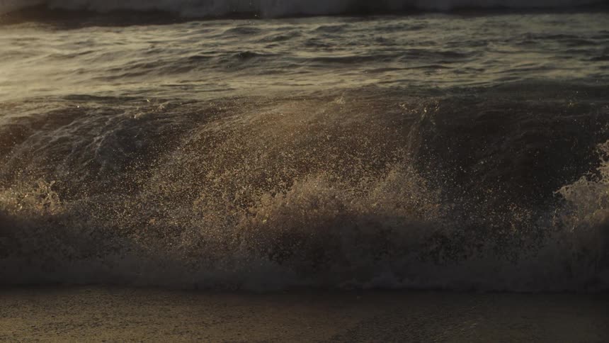 Water sparkles and splashes as waves roll into shore and over the beach