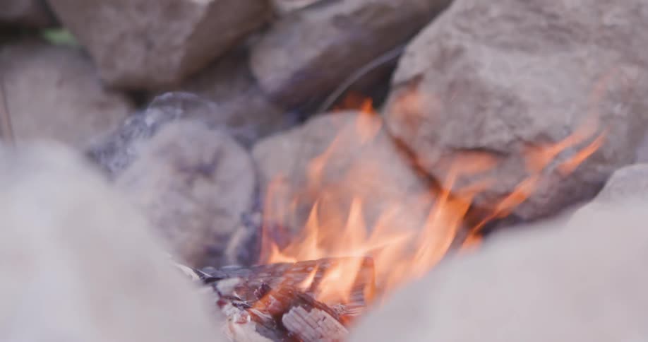 A closeup of a campfire burning in front of a stack of rocks