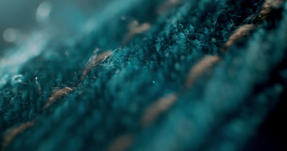 Closeup of a pale thread forming stitches on a denim fabric