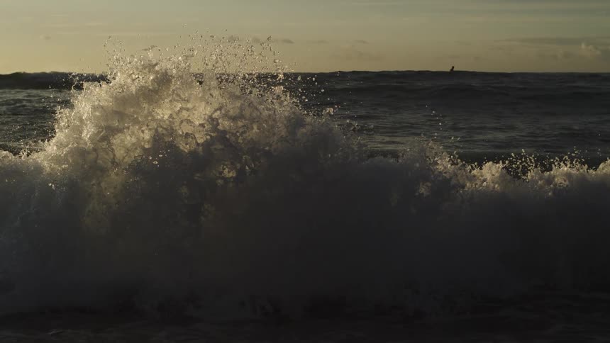 A person riding a surfboard while waves are breaking on the beach