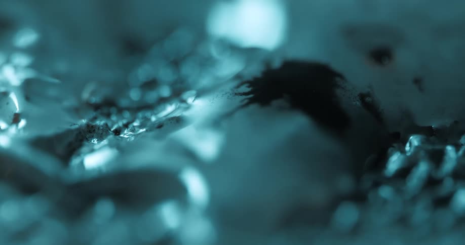 Light shines onto a shadowed white and dark brown mass surrounded by ice