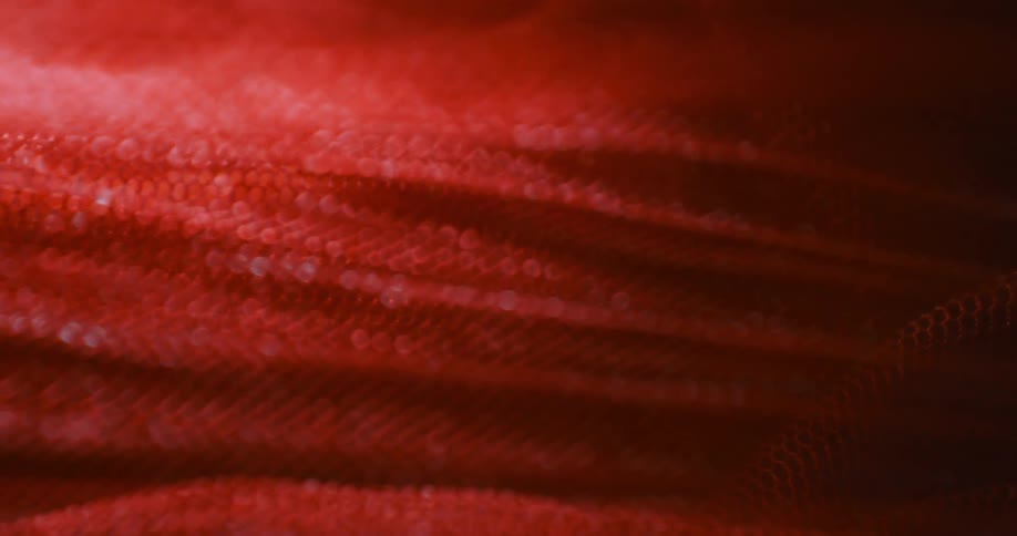 An extreme closeup of a red mesh or fabric texture with soft lighting and abstract patterns