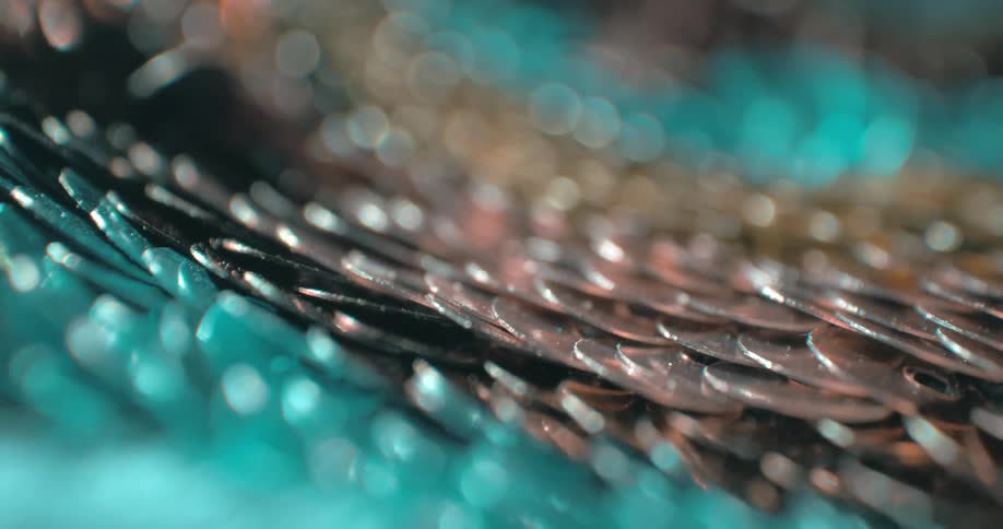 A series of silver coins stacked on top of each other with light reflecting off their polished surfaces