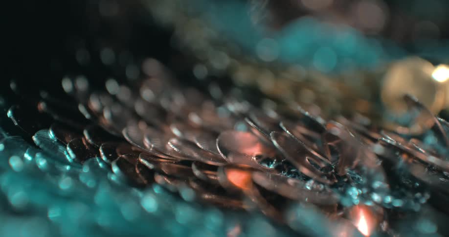 A series of silver spoons stacked on top of each other on a surface with light reflecting off them at night
