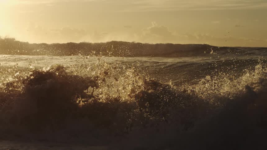 Waves splash into the air as they roll in to shore and over the beach
