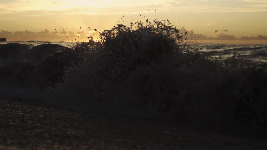 Waves in the sea under a sunset and a cloudy sky