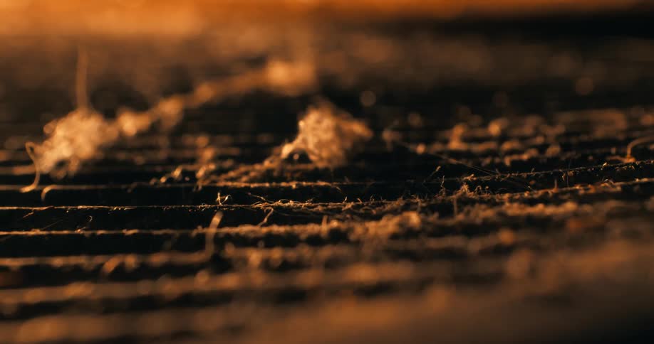Metal grid covered in dust is illuminated by orange light