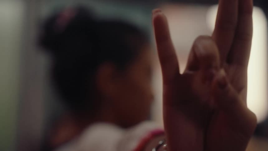 Woman makes hand sign with fingers as she dances from side to side