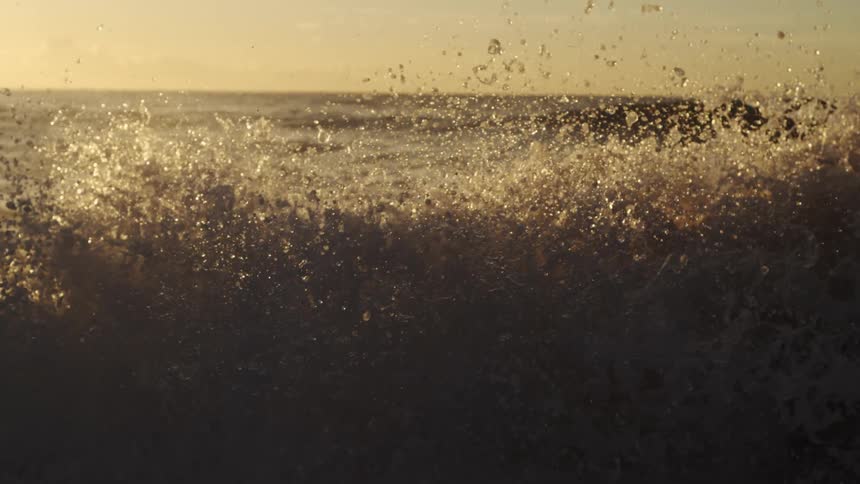 Waves splash and water droplets sparkle as they roll in to shore