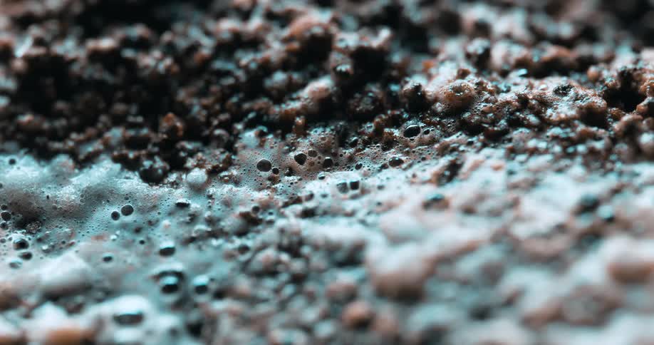 A macro shot showing coffee grounds blooming and bubbling as hot water is poured over them