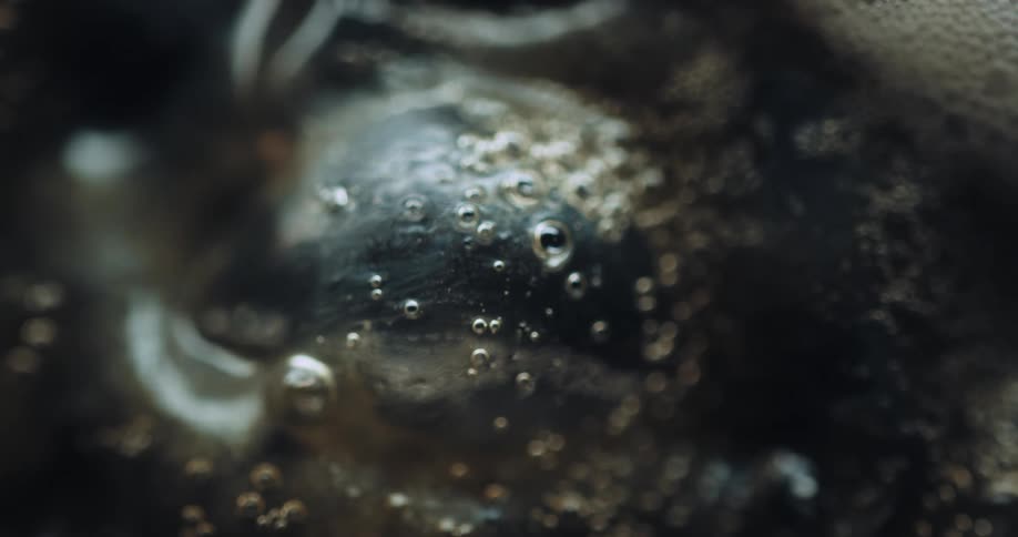 An extreme closeup shot reveals bubbling liquid textures creating an abstract organic visual effect