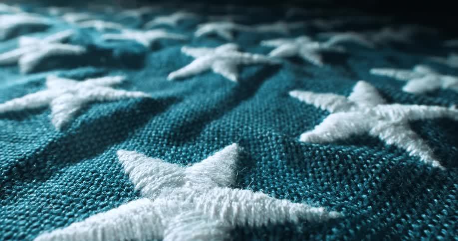 Embroidered white stars contrast with the blue background on the american flag lying on a flat surface