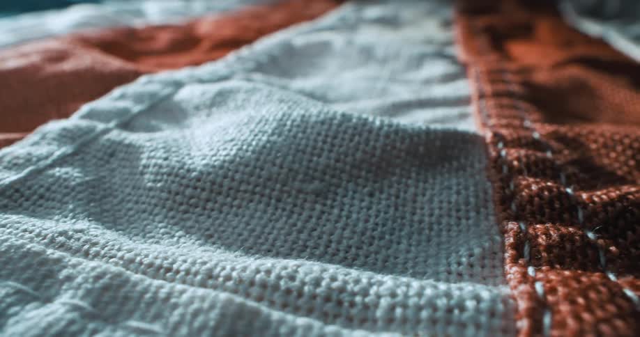 A tightly framed macro shot of textured orange and white fabric highlighting the weave and folds in the material