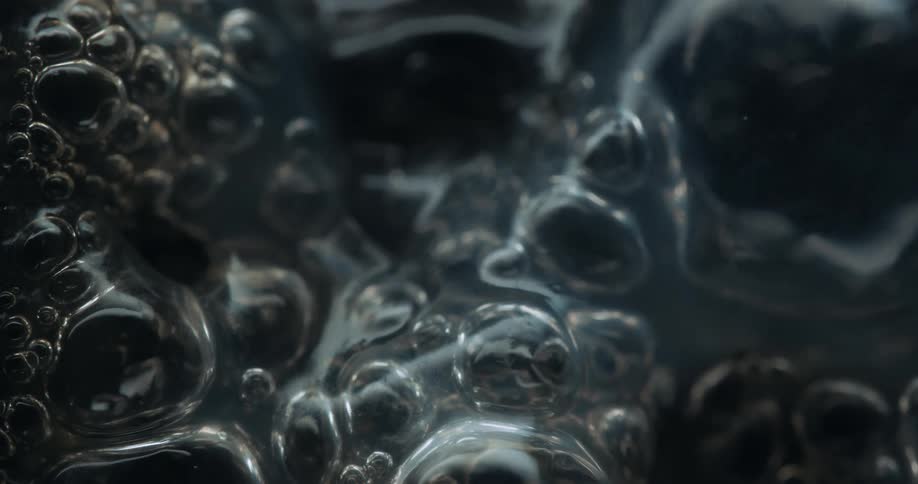 Bubbles form and burst as liquid boils