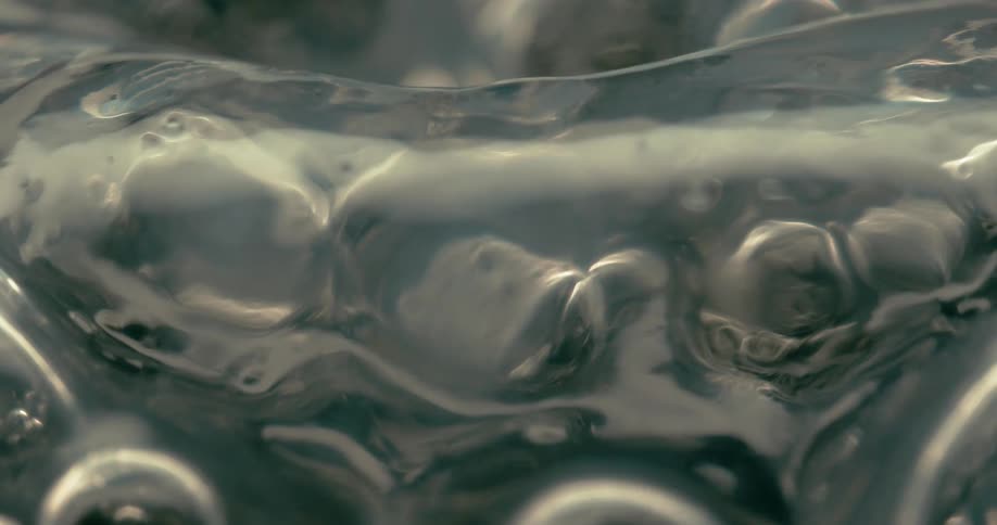 A macro shot captures abstract glossy liquid textures and distorted bubblelike formations in motion