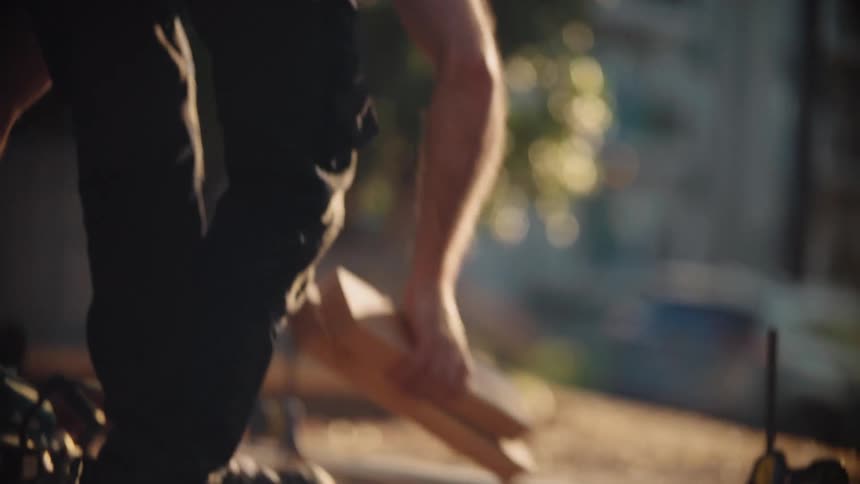 A man is using a circular saw to cut a piece of wood outdoors during the day