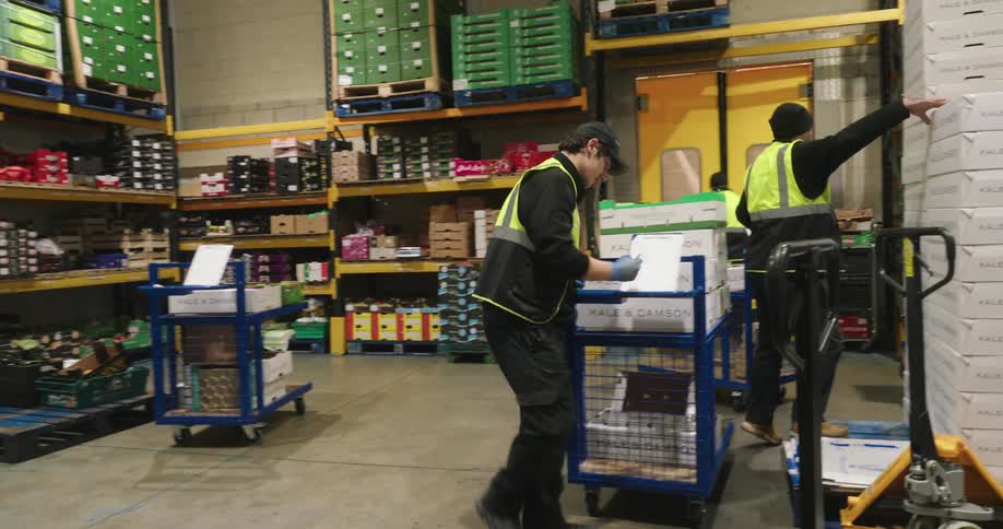 Three men in a warehouse picking up and organizing products