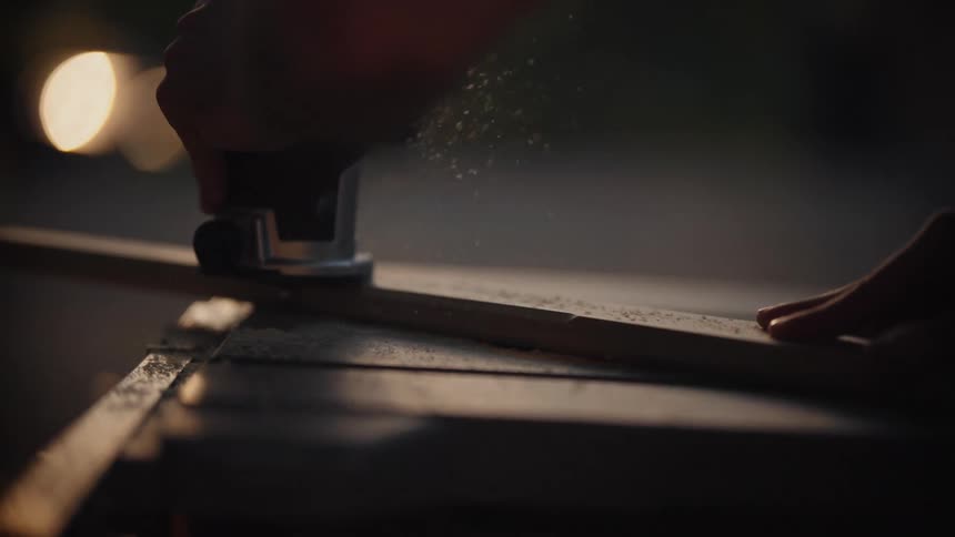 Carpenter uses a sander on a narrow piece of wood