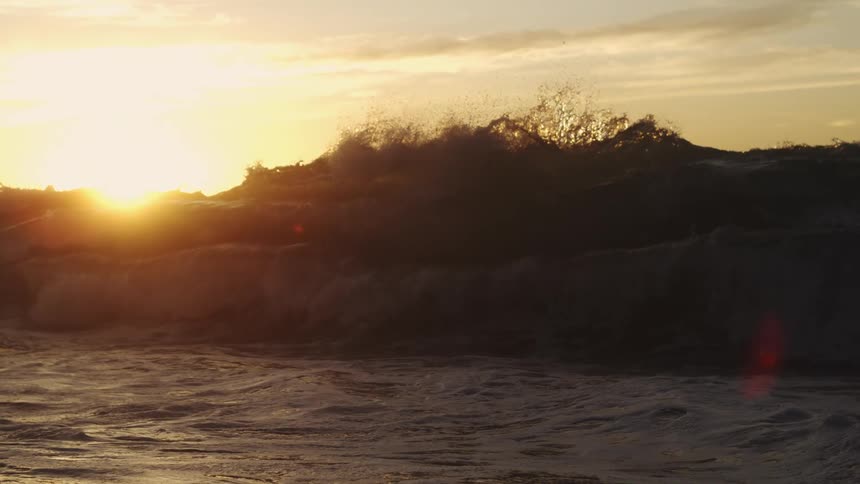 Rough sea with waves and a sunrise in the background