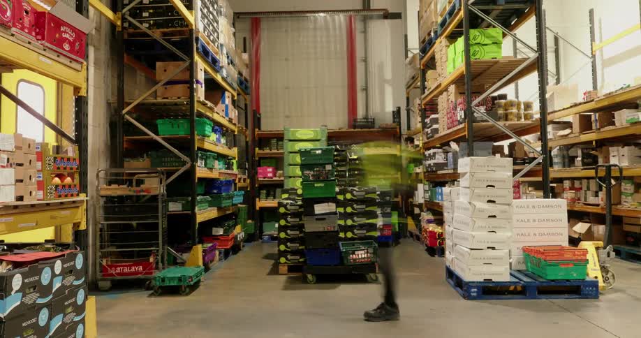Timelapse video showing multiple workers organizing or transporting boxes in a warehouse or storage facility